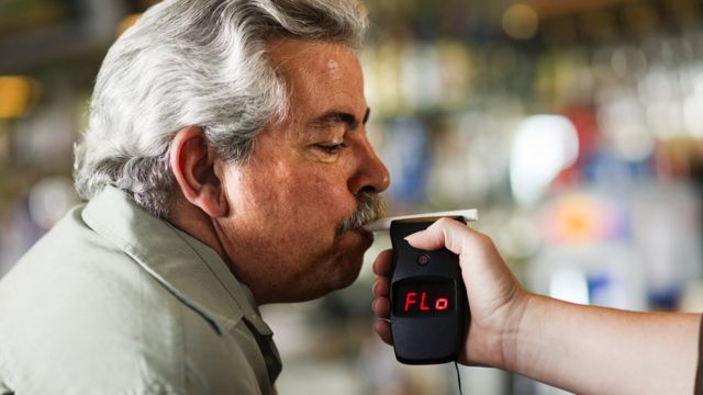 Hombre haciendo una prueba de alcohol con un alcoholímetro.
