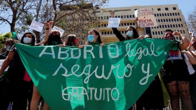 Mulheres na Argentina com um grande tecido verde que diz "Aborto legal, seguro e gratuito"