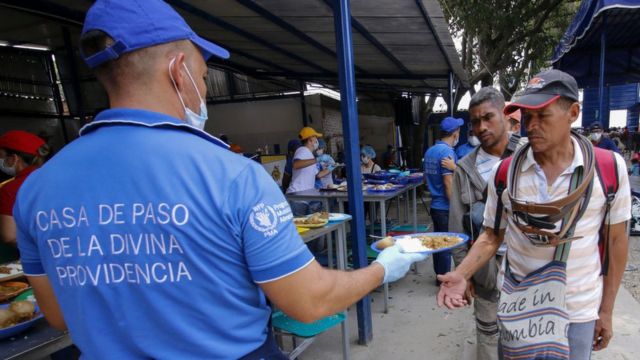 Migrantes venezolanos reciben comida por parte de una ONG.