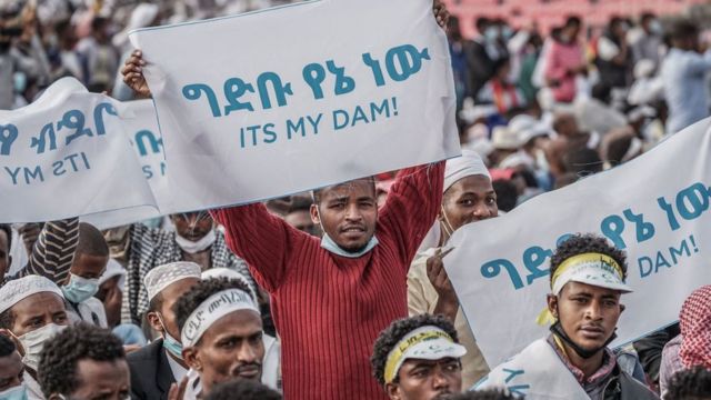 إثيوبيون يحملون لافتات للتعبير عن دعمهم لملء سد النهضة، حيث يتجمع المؤمنون لحضور خطبة صلاة عيد الفطر في ملعب لكرة القدم في أديس أبابا، إثيوبيا ، في 13 مايو/أيار 2021