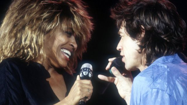 Turner performing a song with Mick Jagger at a concert in 1985