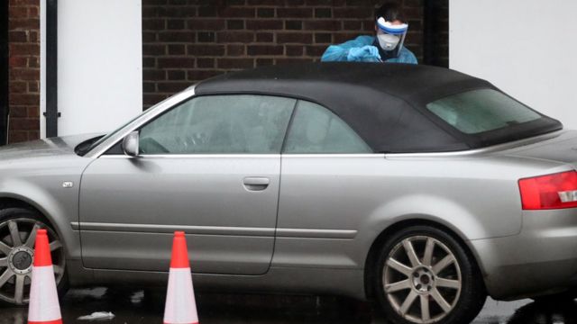 A medical worker carries out a test at a coronavirus drive-through test centre at Parson's Green Medical Centre in London