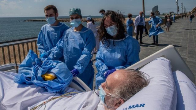 العاملون بإحدى مستشفيات العاصمة الإسبانية يرافقون أحد المرض بفيروس كورونا إلى الشاطىء.
