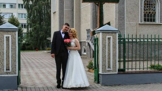Sladjan e Anna posando em frente a uma igreja no dia do casamento