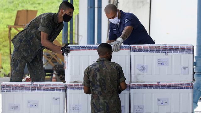 Trabalhadores transportam caixas de isopor com doses de vacina