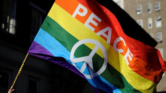 Bandeira colorida com paz escrito em inglês