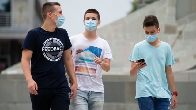 Des adolescents masqués marchent dans la rue à Belgrade, en Serbie