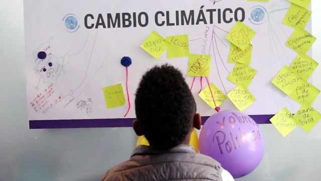 Niño mira un cartel sobre cambio climático