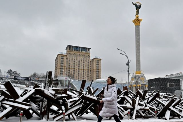 Una mujer camina por barricada antitanque en Kyiv.