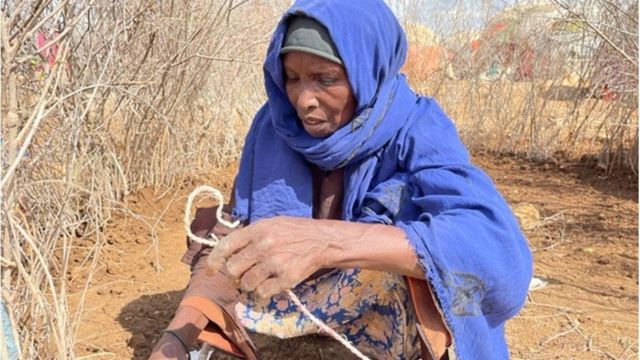 Habiba de cuclillas con un trozo de cuerda en la mano