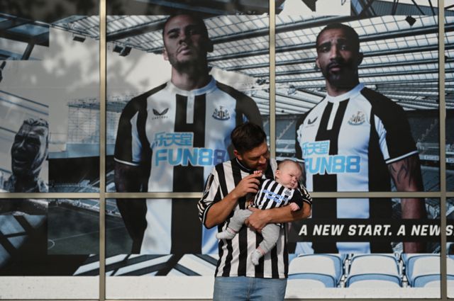 Newcastle United supporter Ryan Arrowsmith poses with three-month old son Lewis outside the club shop at St James' Park in Newcastle upon Tyne in northeast England on October 8, 2021, after the sale of the football club to a Saudi-led consortium was confirmed the previous day.