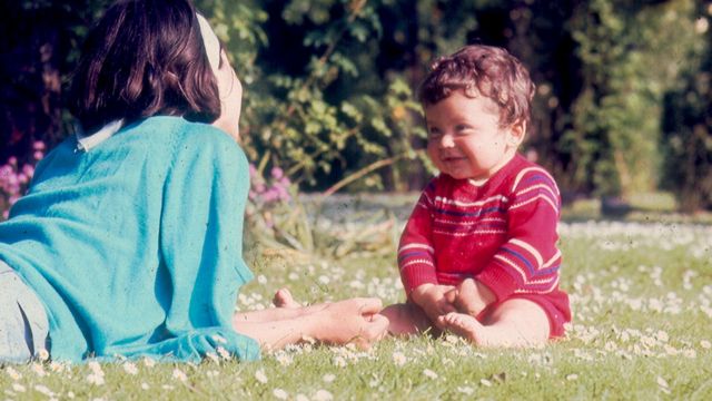 Fotografia tirada por Vladimir Herzog em Regent Park, Londres, junho de 1967. Clarice Herzog, deitada sobre os cotovelos e de costas para a câmera, olha para Ivo Herzog bebê sentado à sua frente, que a olha de volta.