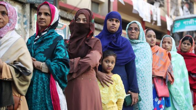 Female voters with children stand in a queue at a voting centre in Dhaka