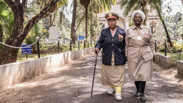 Two Ethiopian war veterans sporting military regalia walk down a path during a memorial service commemorating the anniversary of the 'Addis Ababa Massacre'