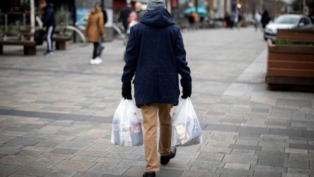 Homem carrega sacolas de compra