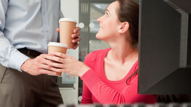 Hombre ofreciendo un café a su compañero de trabajo.
