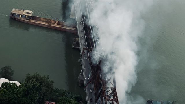 Cột khói xuất phát từ chân cầu Long Biên bay dọc thành cầu.