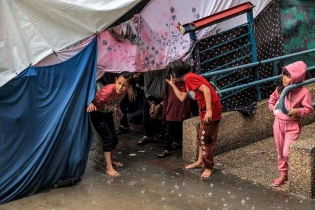 避難民キャンプのテントの下で雨宿りする子供たち（南部ラファ）