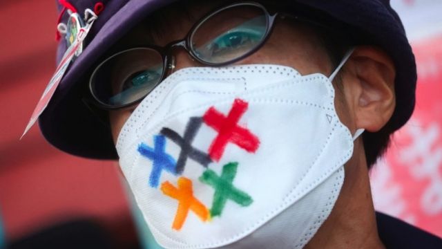 Um homem usa uma máscara com as cores olímpicas em protesto contra os Jogos
