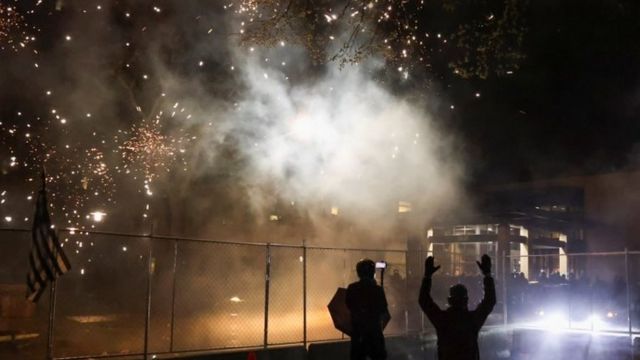 Foto de fuegos artificiales siendo lanzados hacia la comisaría de policía en Brooklyn Center, Mineápolis.