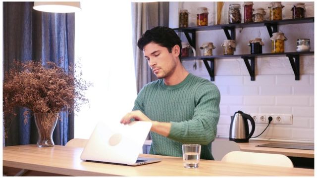 Un joven apagando su computadora