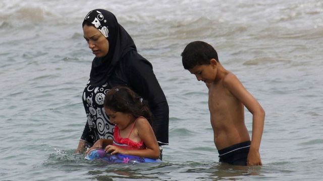 Женщина с детьми на пляже в Марселе одета в буркини