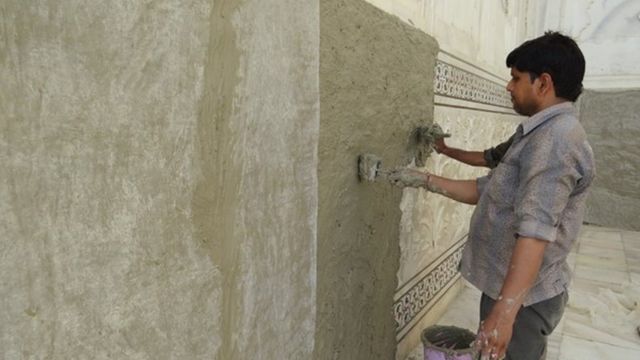 Men apply a "mud pack" onto the Taj Mahal