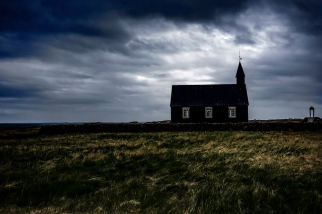 Una iglesia en lo alto de una colina con el trasfondo de un cielo tormentoso.
