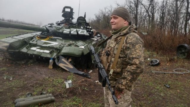 Un soldado ucraniano junto a un tanque ruso destruido.