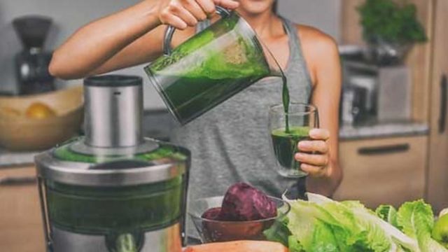 Une femme préparant un jus de fruits ou de légumes