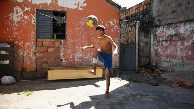 Un adolescente juega fútbol en su casa