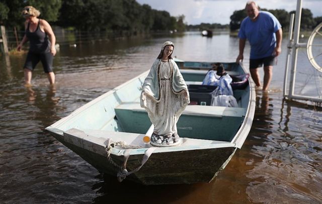 Leigh Babin y su esposo TJ Babin trasladan el barco una estatua de la Virgen María y otros objetos de su casa inundada en Sorrento, Luisiana, EE.UU.
