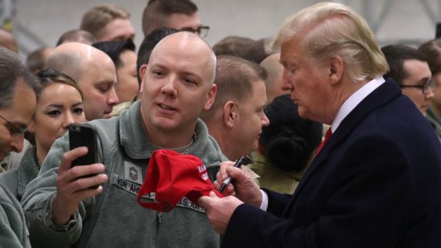 President Donald Trump signs a hat during a visit to Ramstein Air Force Base, Germany, December 27, 2018