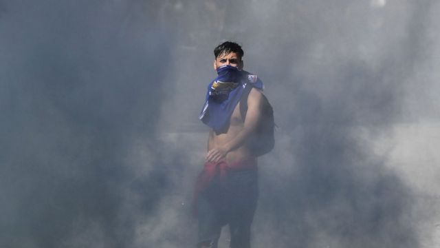 Joven emerge entre la humareda en las protestas en Chile.