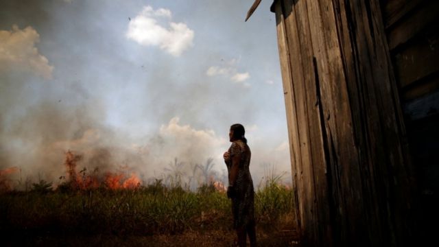 Mulher observando chegada de incêndio próximo à cada dela, em Rondônia