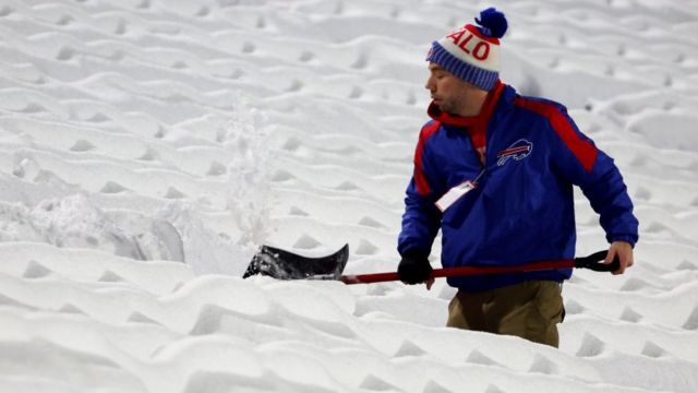 Seorang pria menyekop salju di New York.