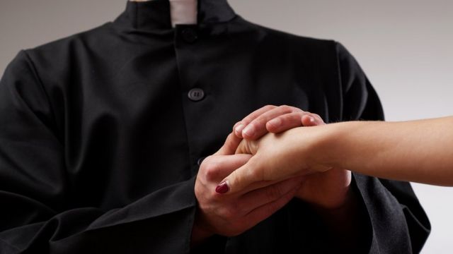 Sacerdote sosteniendo la mano de una mujer