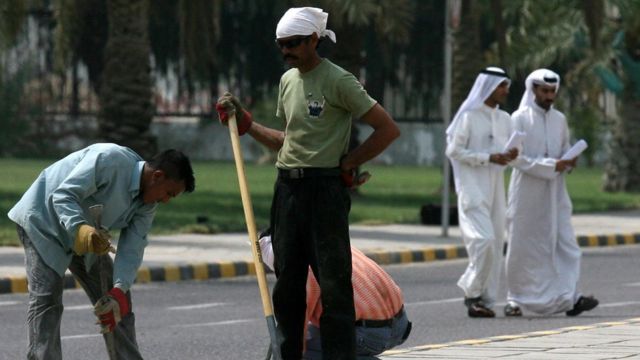 عمال وافدون يعملون في أحد شوارع مدينة الكويت
