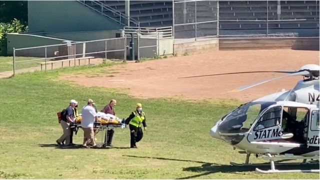 سلمان رشدي أثناء نقله إلى طائرة هليكوبتر في طريقه إلى المستشفى
