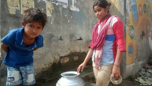 गांव की एक लड़की अपने भाई के साथ पानी भरती हुई
