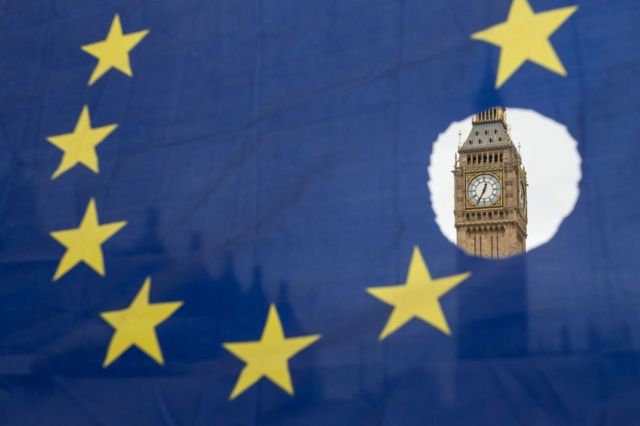 El Big Ben de Londres visto a través de un agujero en la bandera de la Unión Europea.