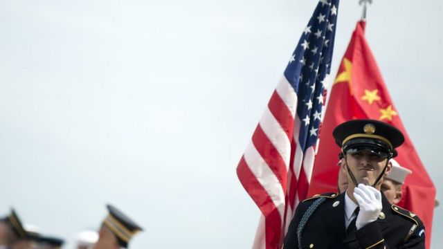 Guardia militar estadounidense lleva una bandera de su país y otro lleva una bandera china.