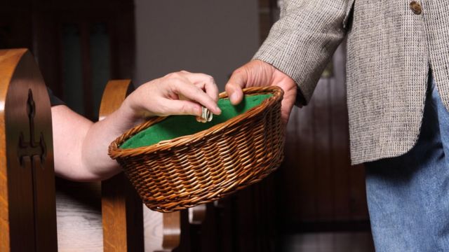 Pessoa recolhendo doa&ccedil;&otilde;es com cesto na igreja