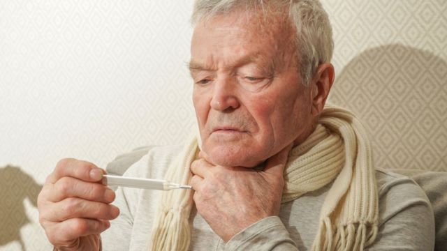 An elderly man takes his temperature