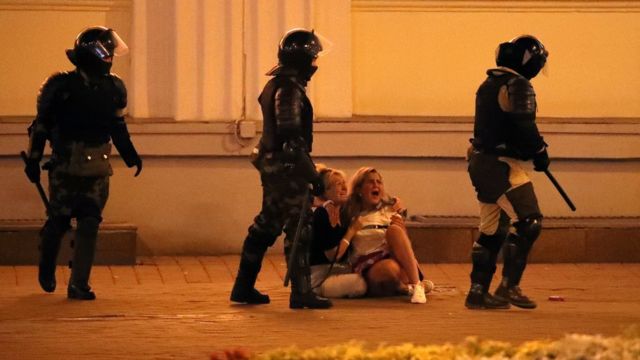 Riot police pass by two crying women during a protest the day after the presidential election, in Minsk, Belarus, 10 August 2020.