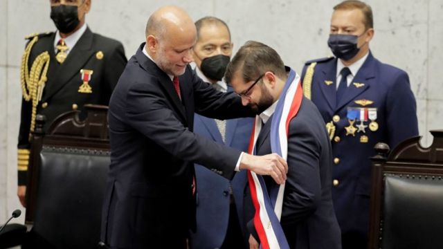 The president of the Chilean Senate, Álvaro Elizalde, hands over the presidential sash to the new president, Gabriel Boric.