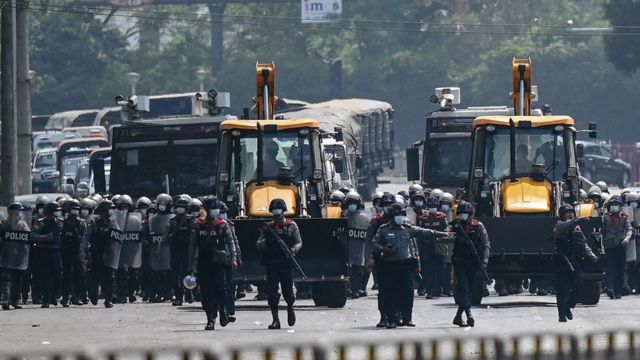 Police advance with heavy construction equipment towards protesters demonstrating against the military coup in Yangon