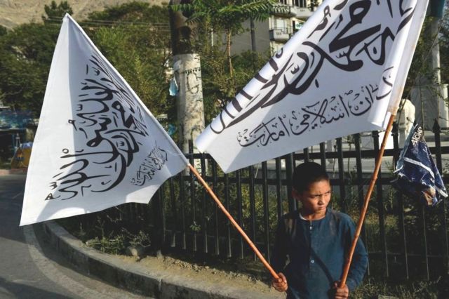 喀布尔的一名男孩拿着塔利班旗帜出售。