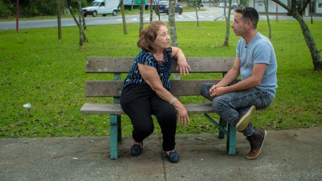 Mãe e filho conversam em banco de praça 