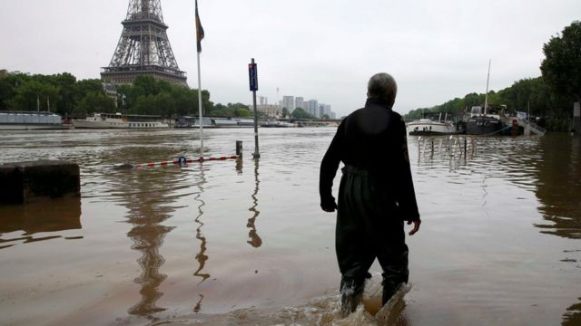 A man walks on a flooded road near his houseboat moored near the Eiffel towel during flooding on the banks of the Seine River in Paris, France